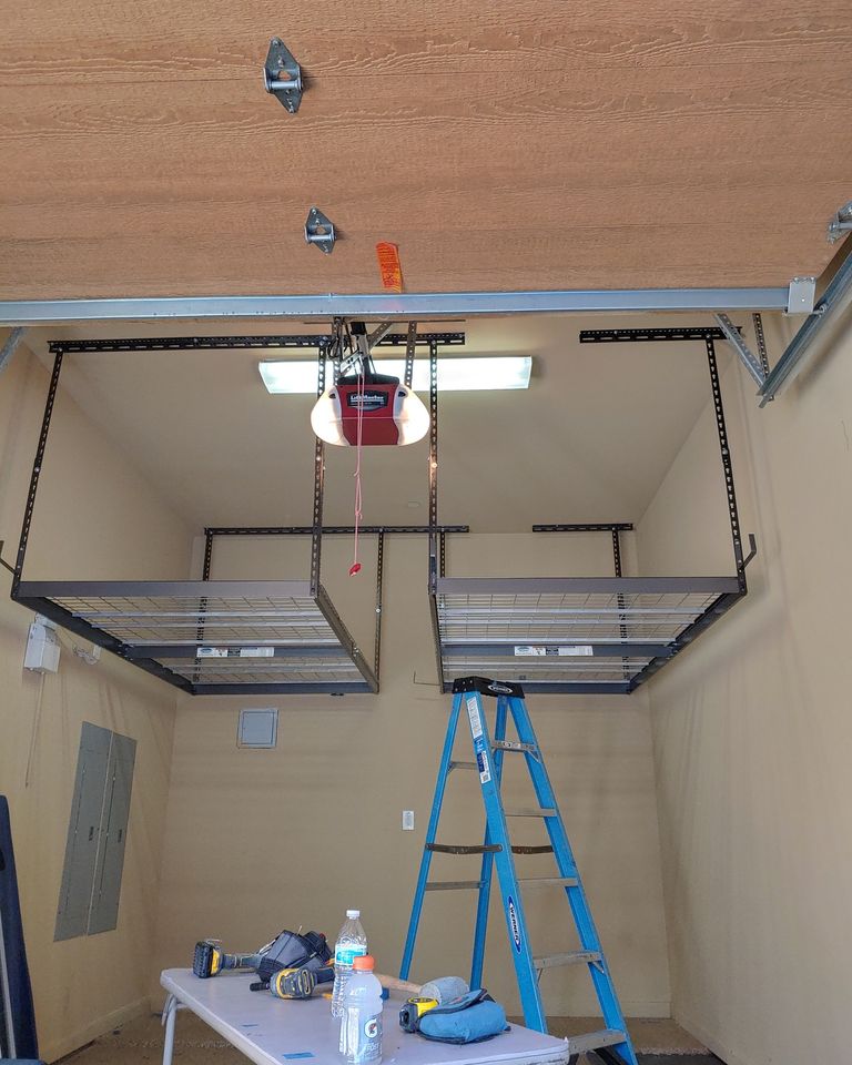 Garage interior with overhead storage, ladder, tools on table, and a hanging light